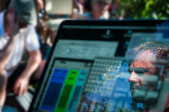 photo du concert en plein air. le visage de l'artiste se reflète dans son ordinateur.